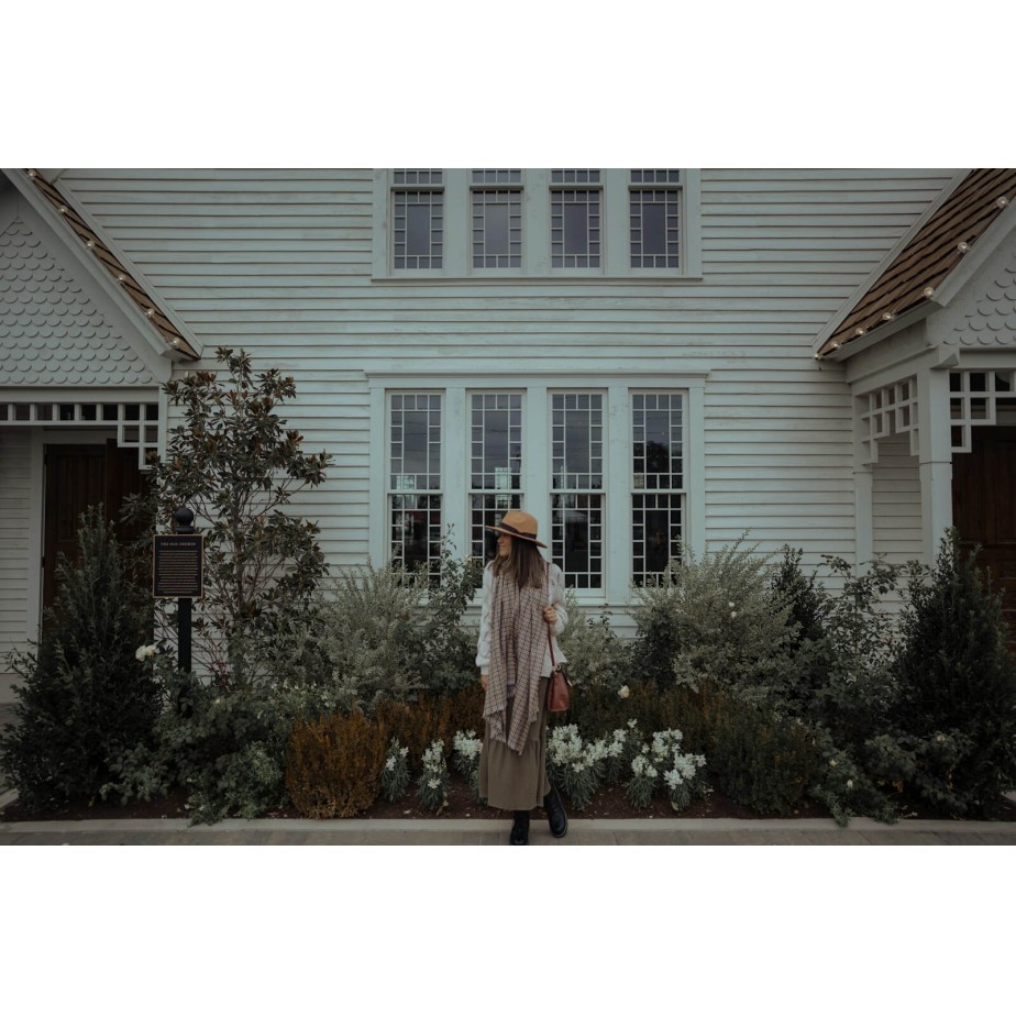 a woman standing in front of a white house