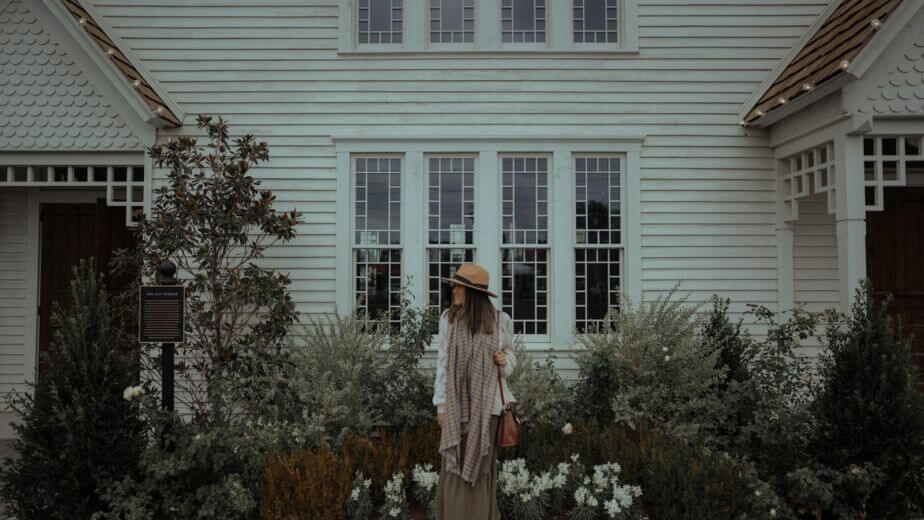 a woman standing in front of a white house