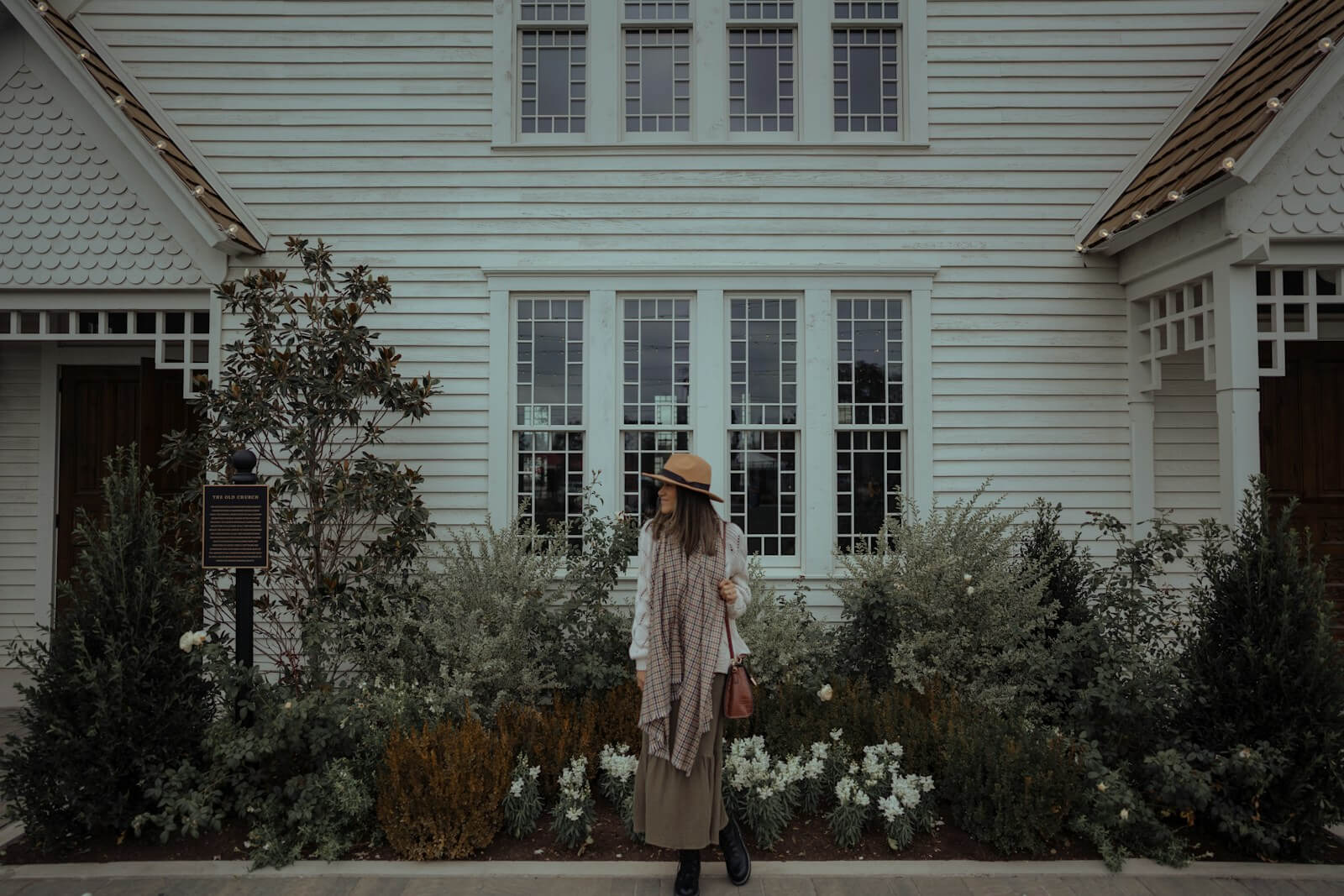 a woman standing in front of a white house